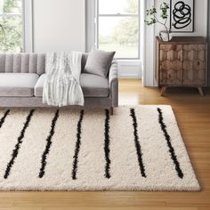 a living room with a gray couch and white rug on the floor next to a window