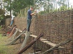 two men working on a fence made out of bamboo sticks