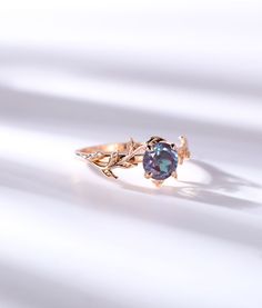 a gold ring with a blue stone in the center and leaves on it's side