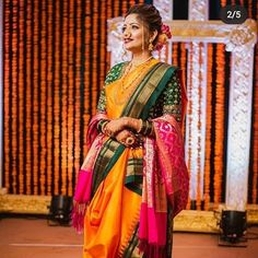 a woman in an orange and pink sari standing next to a stage with flowers on it