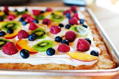 a green bowl filled with fruit on top of a white sauce covered in icing