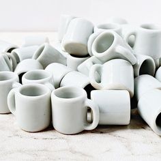 a pile of white coffee cups sitting on top of a table