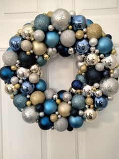 a blue and silver christmas ornament wreath hanging on the front door with ornaments around it