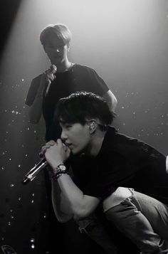 two young men sitting on top of each other in front of microphones and lights