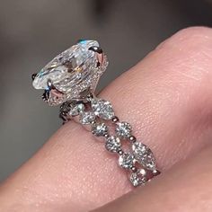 a close up view of a diamond ring on someone's finger, with the center stone surrounded by smaller diamonds