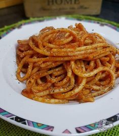 a white plate topped with spaghetti on top of a table