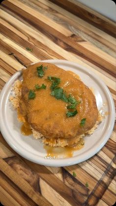 a white plate topped with rice covered in gravy and garnished with parsley