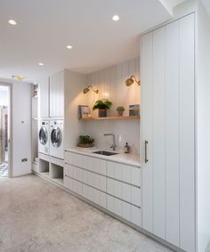 a washer and dryer in a white laundry room with open shelving on the wall