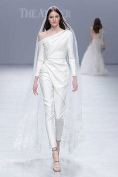 a model walks down the runway in a white outfit with veils on her head