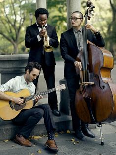 three men in suits are playing instruments outside