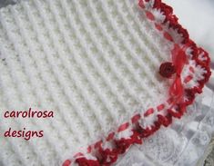 the front cover of a crocheted baby blanket with red and white flowers on it