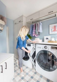 a woman is doing laundry in her kitchen and looking at the washing machine that's open