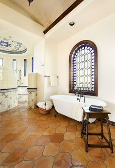 a bathroom with an arched window and tile flooring