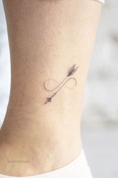 a woman's lower back tattoo with an arrow on her left side ribcage