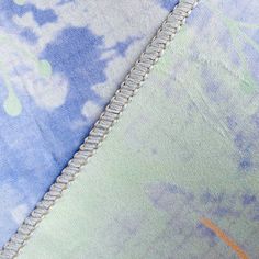 an orange cat laying on top of a blue and green pillow cover with white trim