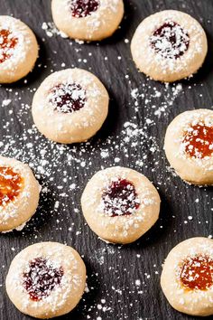 small cookies with powdered sugar and jelly on a black surface, ready to be eaten