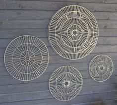 three circular metal wall hangings on a wooden wall next to a chair and potted plant