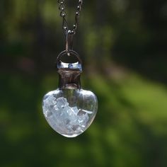 This shaker heart necklace for women is a unique piece of fidget jewelry that captivates with its Icy blue glass shards encased in a stunning glass heart pendant. The shards move freely within the pendant, offering a soothing and mesmerizing effect, perfect for those who enjoy tactile experiences. This exquisite necklace makes an ideal coworker promotion gift, combining elegance with a touch of playful charm. Icy blue glass shards fill this hand blown glass heart bottle. The blue glass moves freely inside making this pendant both eye catching as well as uniquely interesting. Hand formed and soldered bail and cap. The top is sealed and cannot be opened. Custom requests welcome.  * Pendant dimensions: 1 1/2"H x 1"W (38 x 25mm)  * Your choice of chain length, select at checkout. 22", 24" and Silver Glass Jewelry With Heart Charm, Valentine's Day Silver Glass Necklaces, Valentine's Day Silver Glass Necklace, Silver Glass Necklace Keepsake, Silver Glass Necklace For Keepsake, Adjustable Glass Heart Pendant Jewelry, Clear Glass Heart Pendant Necklace, Glass Heart Beads Necklace As A Gift, Clear Heart Charm Necklace With Heart Pendant