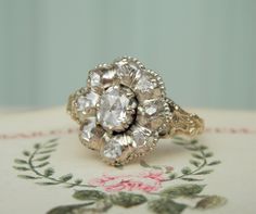 I am delighted to announce our new listing, here we have a fine antique Georgian cluster ring. This ring has such a romantic feel with its floral vibes and this style is the forebear of the daisy cluster that became so popular in the Victorian and Edwardian periods. I have been searching high and low for a piece like this in the right condition and this ring really does deliver. This handmade ring is designed around a central rose cut diamond set within a surround of smaller rose cuts.  Rose cut diamonds originated around the 16th Century. They were inspired by the spiral of petals in a rose bud. Instead of a tight sparkle like a modern round brilliant cut, rose cuts are more known for a sensual shimmer and luster. Rose cut diamonds have a domed top and a flat base... and much like the spr Floral Diamond Ring, Rose Bud, Professional Jewelry, Hand Model, Antique Boxes, Small Rose, Wedding Wishes, Modern Round, Diamond Cluster Ring