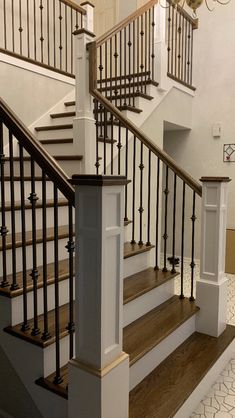 a white staircase with black railing and wood handrails