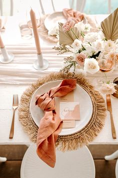 the table is set with white plates and pink napkins, gold place settings, and flowers