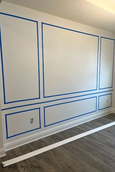 an empty room with blue lines painted on the wall and wood flooring in front of it