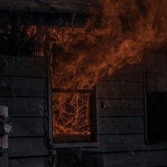 a fire hydrant in front of a house with flames coming out of the windows