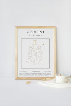 a framed poster with the zodiac sign for germini on it next to a candle