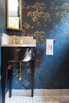 a sink and mirror in a room with blue wallpaper, gold trimmings