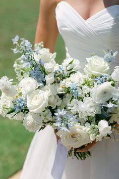 a bride holding a bouquet of white and blue flowers