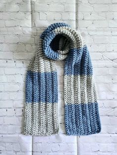 a blue and white knitted scarf hanging on a brick wall in front of a white brick wall