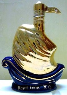 a gold and blue vase sitting on top of a white table next to a wall