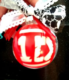 a close up of a person holding a christmas ornament with the letter d on it