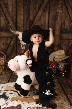 a little boy in a cowboy hat sitting on a toy cow