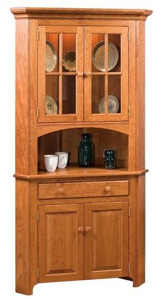 a wooden hutch with glass doors and plates on it's side cabinet,