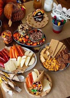 a table filled with lots of food and candy on top of paper plates in front of pumpkins