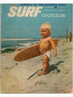 a young child holding a surfboard on top of a sandy beach