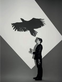 a man standing in front of a black and white image of a bird flying over his head