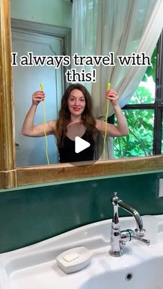 a woman standing in front of a bathroom mirror holding up two yellow hairdryers