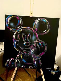 a mickey mouse painting on top of a easel