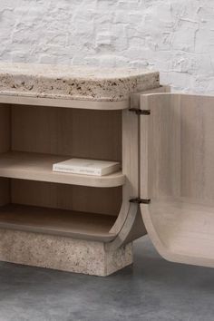 an open shelf with a book on it in front of a white brick wall and floor