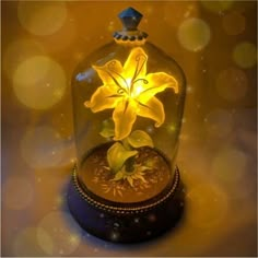 a yellow flower under a glass dome with lights on the top and below it is a gold plated clock