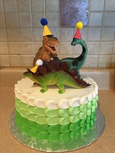 a birthday cake decorated to look like a dinosaur and a t - rex riding on it