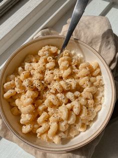 a bowl filled with macaroni and cheese on top of a window sill