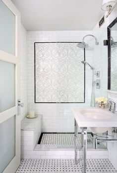 a white bathroom with black and white tile flooring, a shower stall and sink