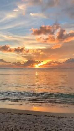 the sun is setting over the ocean with clouds in the sky and on the beach