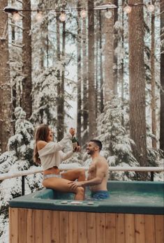 a man and woman are sitting in the hot tub drinking champagne while they look at each other