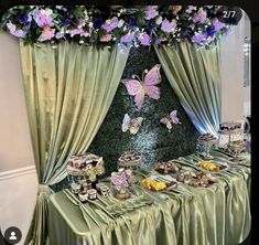 a table topped with lots of food covered in green cloths next to a curtain