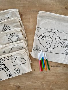 three bags with colored pencils sitting next to each other on a wooden table,