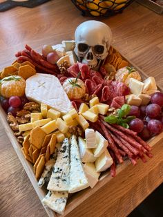 a platter with cheese, meats, and other food items on a wooden table